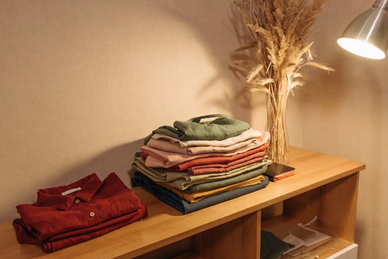 Ropa doblada y acomodada sobre un mueble de madera en un espacio doméstico ordenado y sereno.