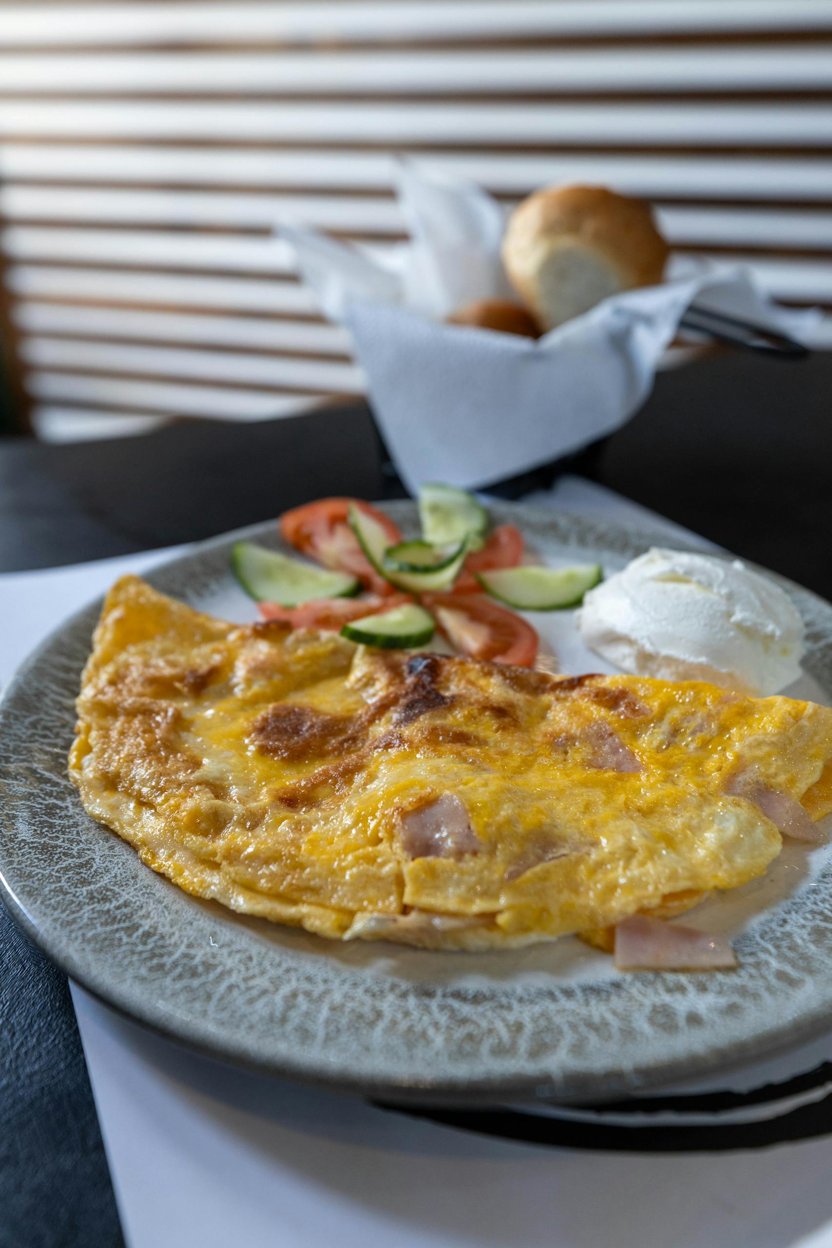Omelette de jamón servido con tomate y tostada.