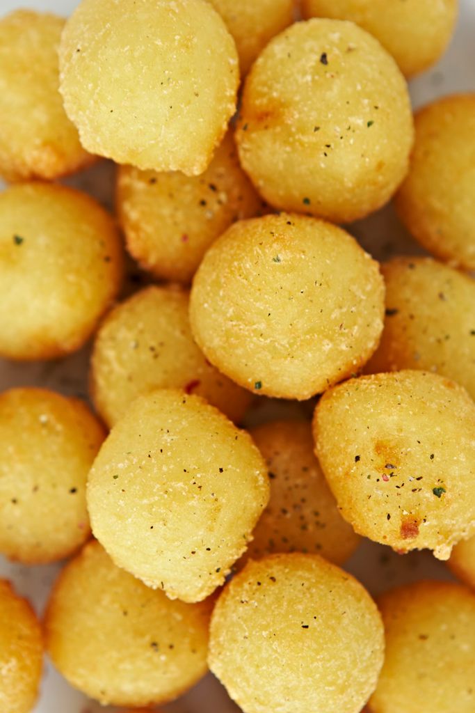 Bolitas de queso doradas servidas en primer plano, con textura suave y ligeramente crujiente.