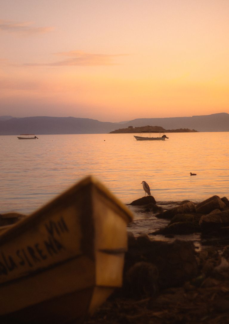 Atardecer tranquilo en el Lago de Chapala, cerca de Mezcala, Jalisco, México, con barcas y aves sobre el agua.