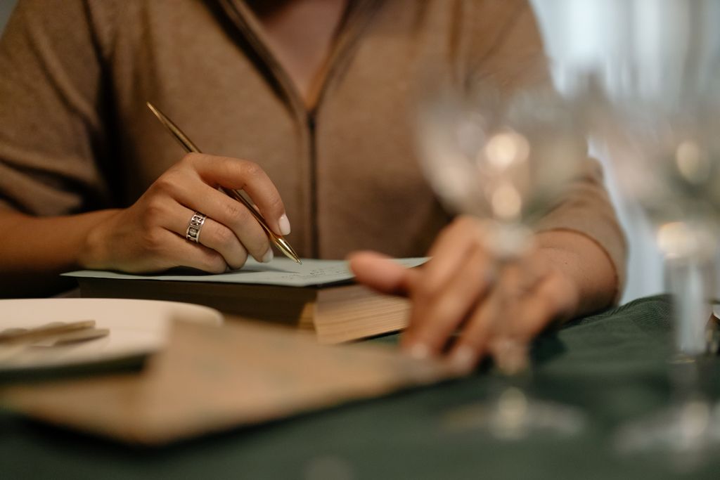 Persona escribiendo una nota a mano sobre una mesa durante una dinámica del ritual de las dos luces.